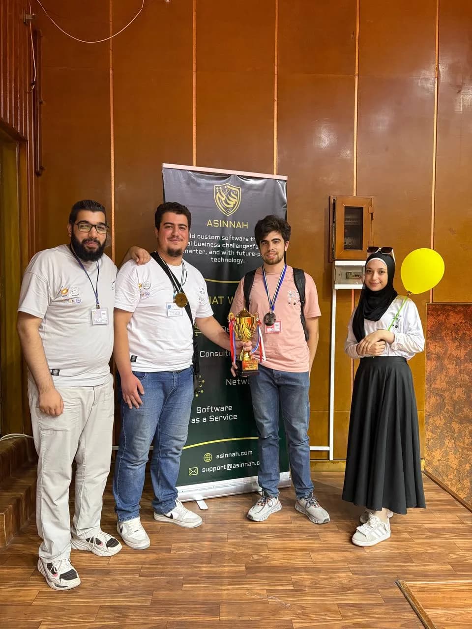 The Asinnah team holding their award beside the company banner at a hackathon in Homs